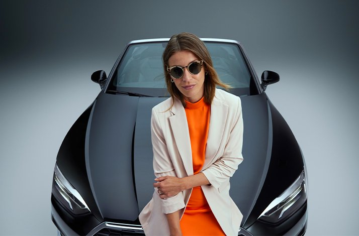 The lady sitting on a black convertible car, as part of a promotional campaign for a rental service SIXT.