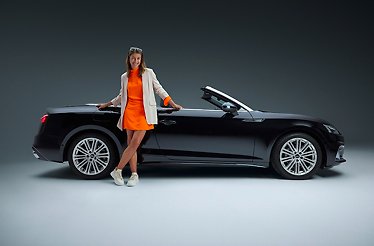 The lady leaning on a black convertible car, as part of a promotional campaign for a rental service SIXT.