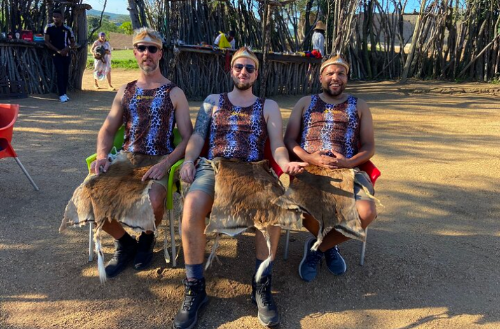 Three visitors wearing traditional leopard print shirts and animal skins in Hazview.