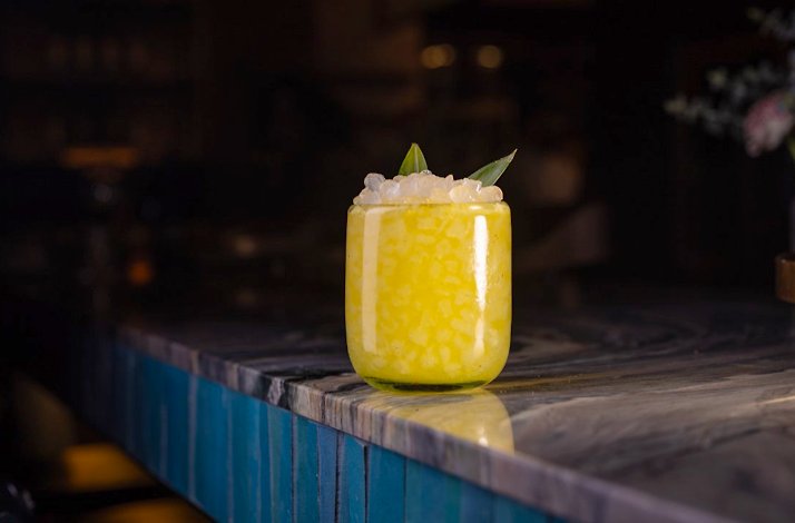 An elegant yellow cocktail topped with mint and crushed ice, served at Loreto.
