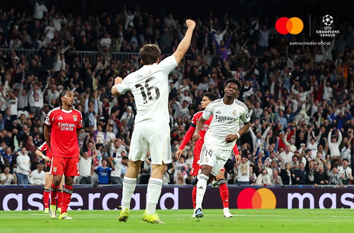 Player wearing number 16 raising fist during a UEFA Champions League match, with a packed crowd cheering in background.