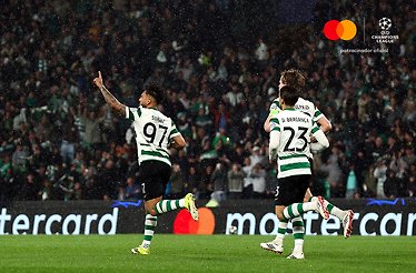 Sporting CP's Suarez pointing skyward in celebration alongside D. Braganca during UEFA Champions League Round of 16 second leg.