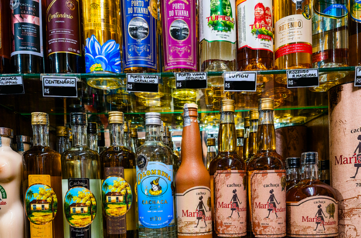 Shelves filled with various bottled cachaça liquors, showcasing colorful labels and distinct brand logos.
