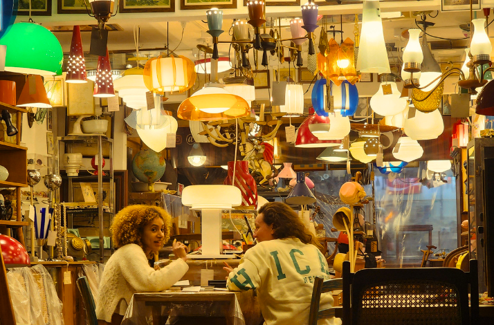 People enjoying drinks at a bar filled with lamps.