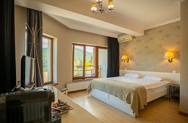 Opus View Sinaia room featuring a double bed, floral accent wall, parquet floors, and panoramic mountain window views.