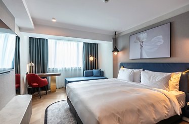 Stylish hotel room at Lotus Therm Spa & Luxury Resort featuring a sofa nook, pendant lighting, a writing desk, and blue-toned decor.