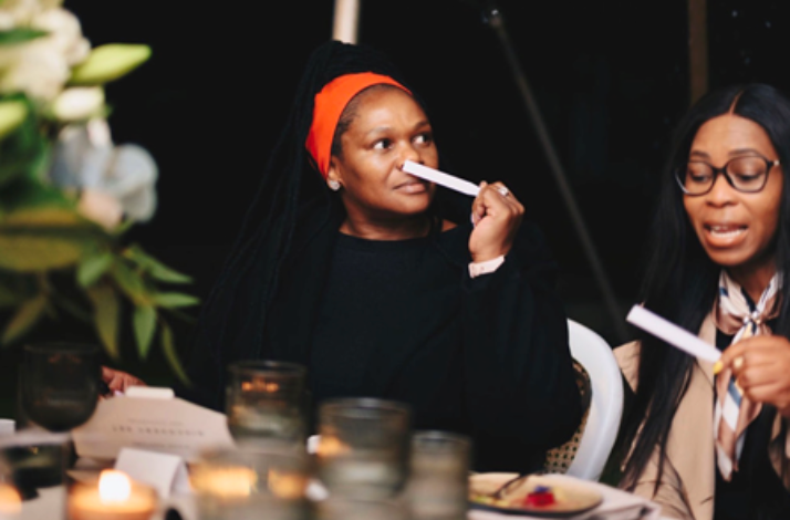 Two guests inhaling fragrance strips at a candlelit table during the Niche Parfums scent-pairing course at Chef Black's event.
