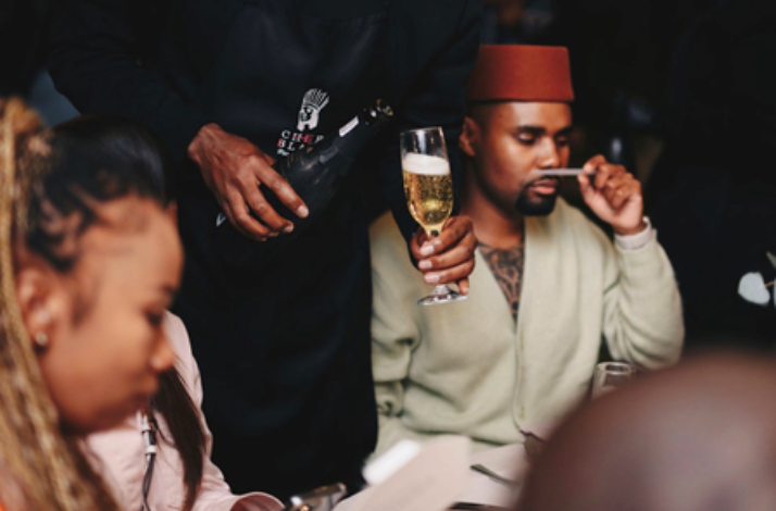 Event attendee savouring a fragrance strip alongside a glass of champagne during the multicourse sensory dining experience.