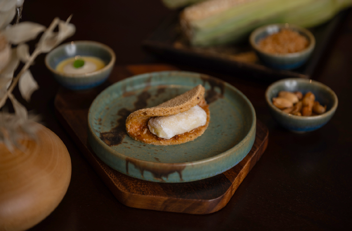 Elegant Malaysian-inspired dish featuring a crisp cracker, creamy filling, and accompaniments served on a teal ceramic plate at Akar.