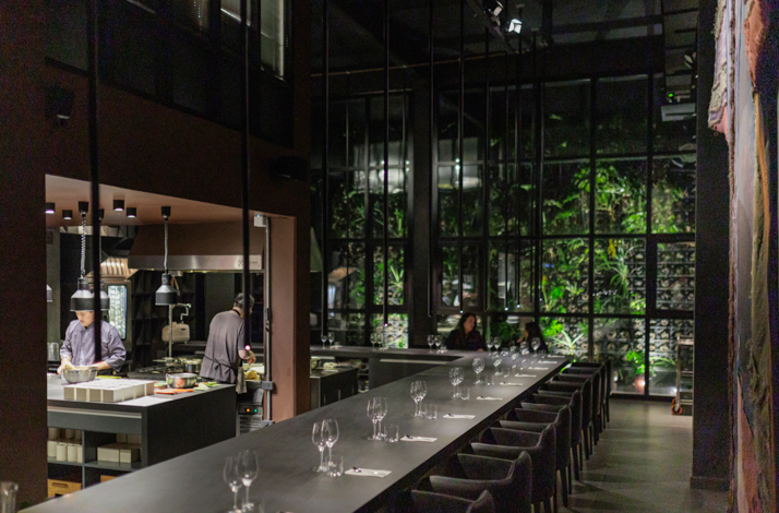 Interior of Han restaurant featuring an intimate chef's counter overlooking the open kitchen, where guests enjoy a contemporary Korean dining experience in a sophisticated setting.
