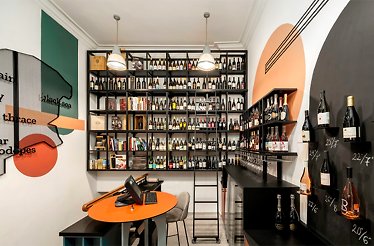 Well-stocked Wine Generator retail space featuring floor-to-ceiling bottle shelves, chalk date displays, and bold graphic wall murals.