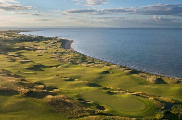 Aerial photo of a seaside links golf course with rolling dunes and a green near the coastline.