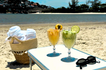 Two cold cocktails in a table with glasses and towels at the beach with the mangrove as the view