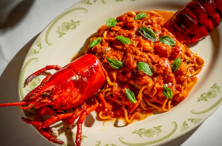 Lobster fra diavolo with spaghetti in rich tomato sauce, garnished with fresh basil leaves, served at Opto.
