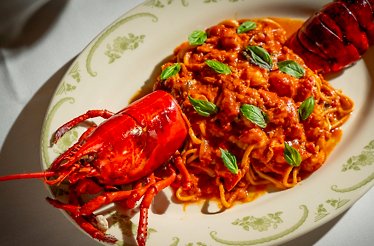 Lobster fra diavolo with spaghetti in rich tomato sauce, garnished with fresh basil leaves, served at Opto.