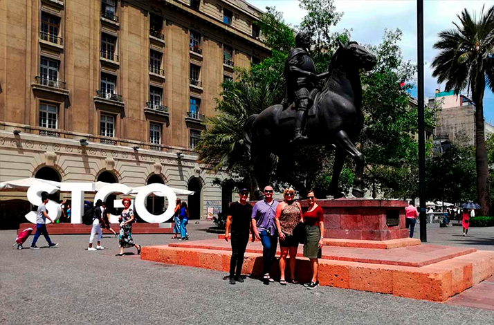 Travelers exploring Santiago's historic center beside the equestrian statue at Plaza de Armas, discovering the city's heritage, architecture, and local culture on foot.