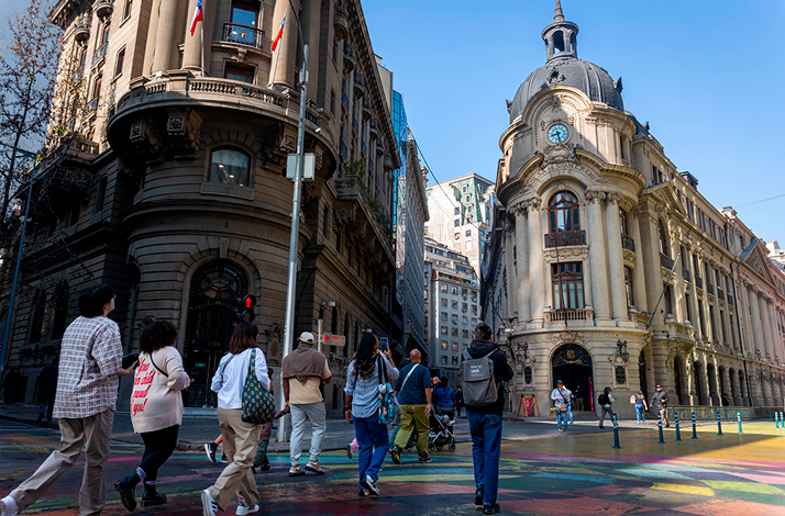 Travelers crossing a downtown Santiago street surrounded by iconic historic buildings, experiencing the city's architecture, history, and daily urban life