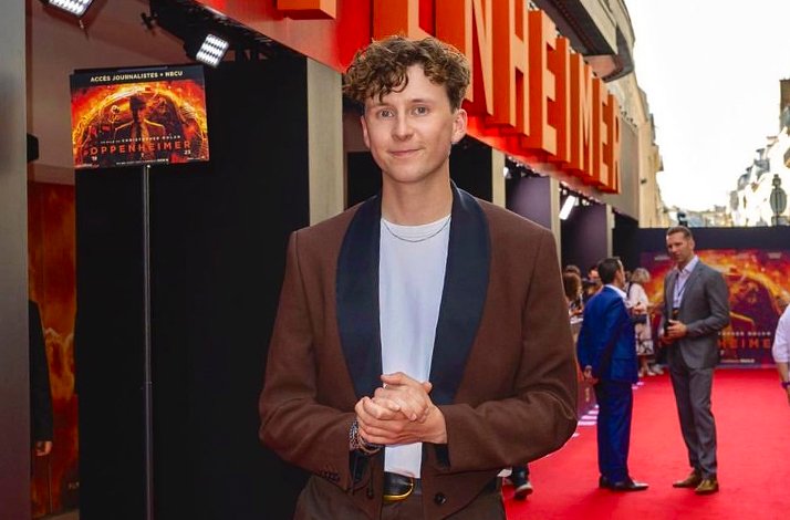 Thomas Duke posing on the red carpet at the Oppenheimer movie premiere.