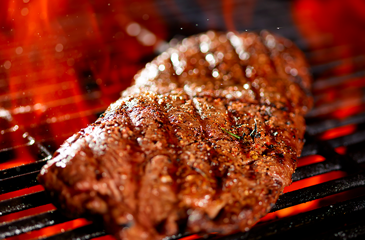 Traditional Argentine asado meats grilling over open flames with fresh lemon.