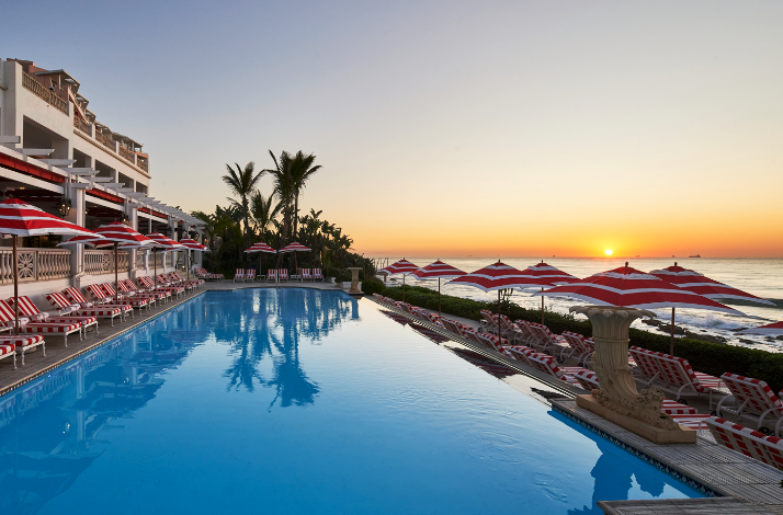 Infinity pool at sunset with red-and-white loungers overlooking the ocean