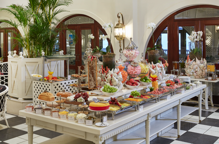 Breakfast buffet table with fruit, pastries, and cheeses in an elegant dining room.