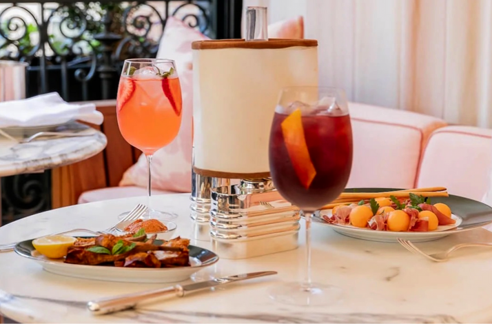Two fruit-garnished cocktails and light bites arranged on a marble dining table at Casa Cruz New York.