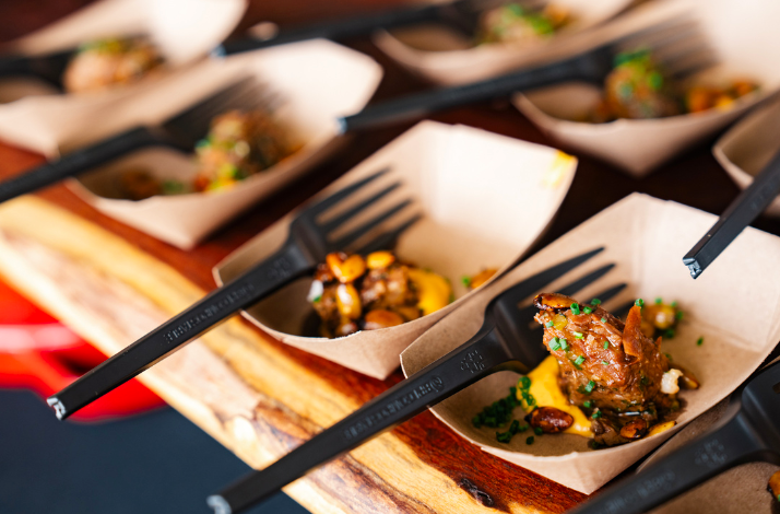 Rows of small cardboard trays holding grilled meat with some fresh sides, served at Austin Food and Wine Festival.