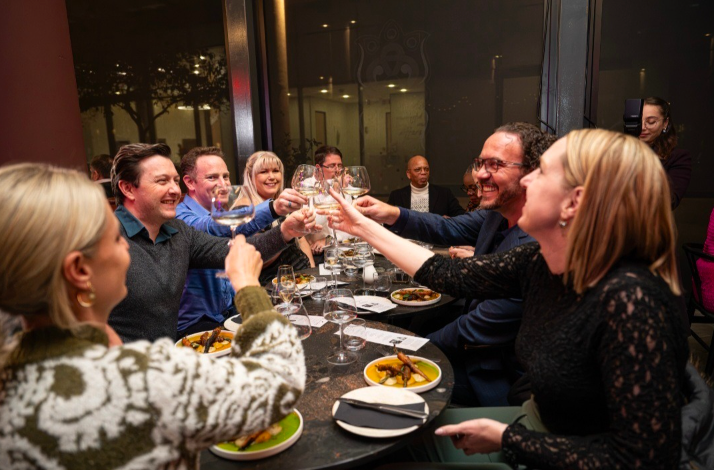 A group of guest toast socially in communal dining vibe.