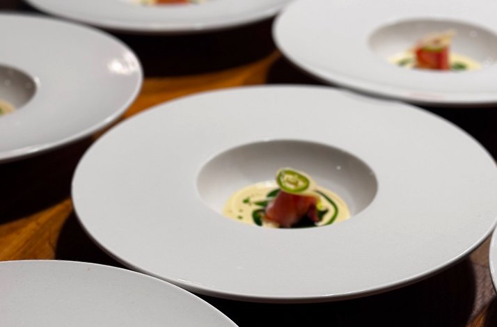 Zitz Sum tasting menu plating lineup showing minimalist wide bowls with seared fish, cream, and sliced jalapeno garnish.