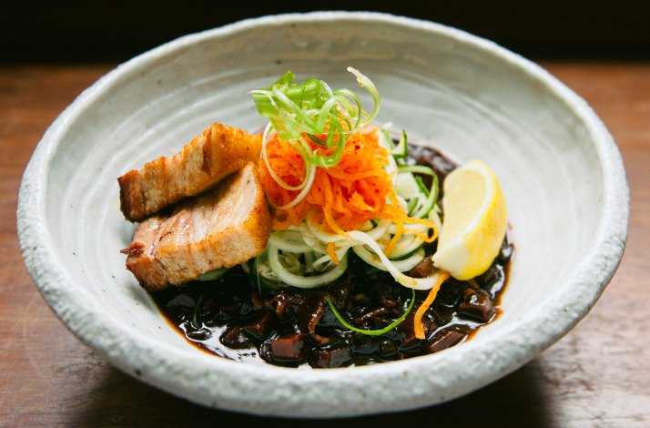 Korean jajangmyeon dish with sliced pork belly, shredded carrots, cucumber noodles, black bean sauce, and lemon wedge. 