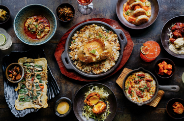 Overhead spread of Korean-inspired shared plates, skillet rice, and cocktails at Pace NYC