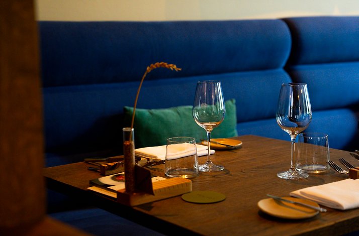 Interior dining setup at Restaurant Lokaal, Netherlands, with wine glasses, cutlery, and a bold blue upholstered bench seat.