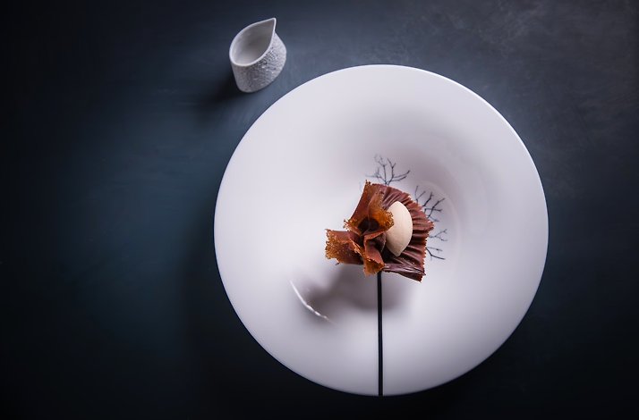 Chef Michael Cimarusti's sculptural chocolate dessert with ruffled tuile and cream sphere on white plate at Providence.