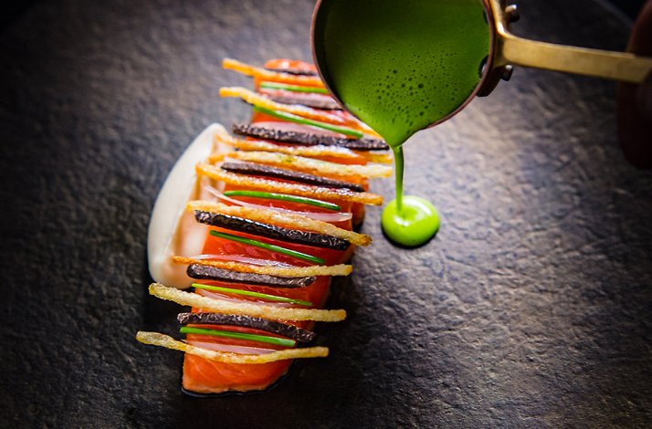 Chef Michael Cimarusti's king salmon with black truffle, green herb sauce being poured tableside at Providence.