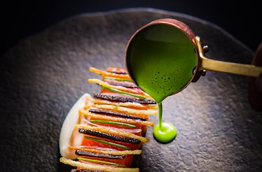 Chef Michael Cimarusti's king salmon with black truffle, green herb sauce being poured tableside at Providence.
