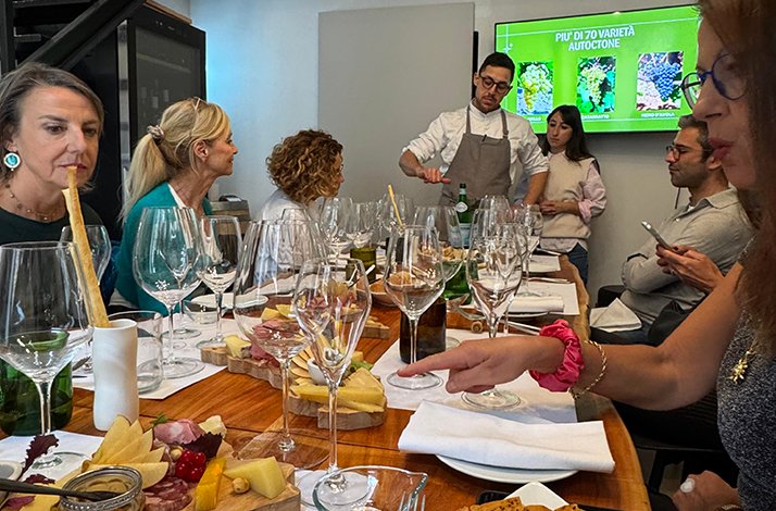 Wine tasting session at A'Cuncuma restaurant in Palermo, with guests seated at a table set with charcuterie boards and wine glasses.