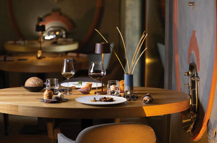 Elegantly set round wooden table with wine glasses, plated Tuscan courses, and dried-stem centerpiece at Ps Ristorante.