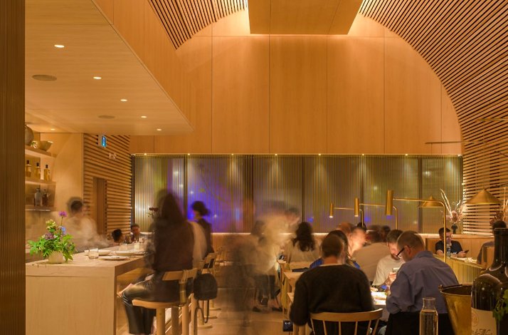 Warm wood-lined dining room at Prime Seafood Palace, with arched ceiling and diners seated at tables.