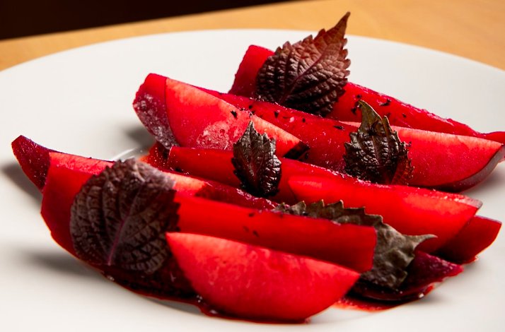 Bright red beet wedges garnished with dark leaves on a white plate, served at Prime Seafood Palace.
