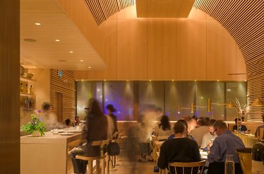Warm wood-lined dining room at Prime Seafood Palace, with arched ceiling and diners seated at tables.