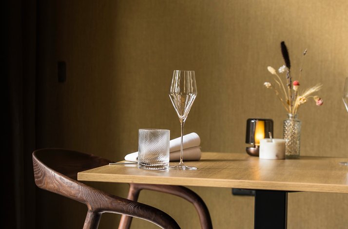 Restaurant Fris interior: wooden table set with wine glass, water glass, napkin, candle, and small dried flowers.
