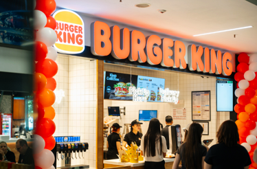  Burger King restaurant entrance in a mall, decorated with orange and white balloons, with 'Pick Up Here' and 'Delivery Pick Up' signage.