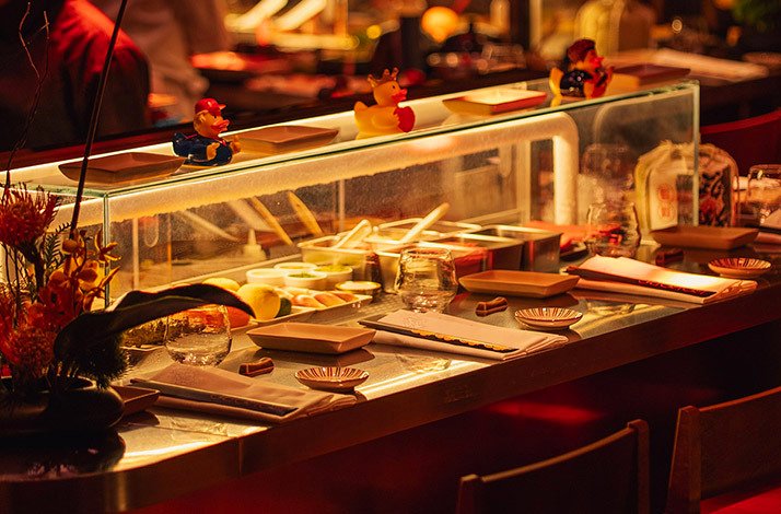Sushi bar counter with glass ingredient displays and themed rubber ducks at Kokoro Hand Roll Bar, Dubai.
