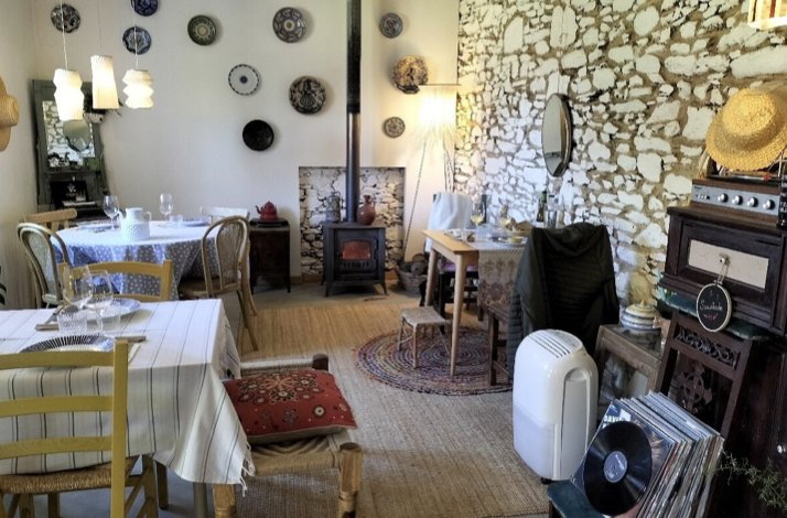 Rustic dining room at O Balado with stone walls, decorative plates, set tables, wood stove and vinyl records.