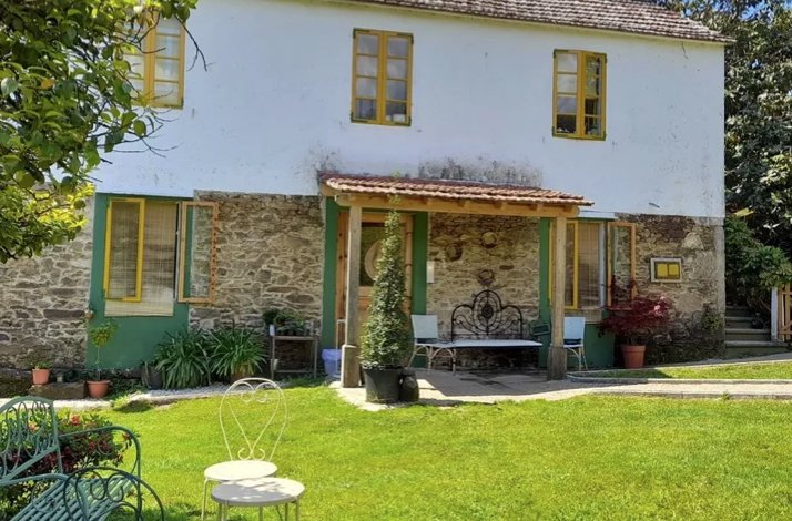 O Balado restaurant's rustic stone exterior featuring yellow window frames, garden seating and green lawn.