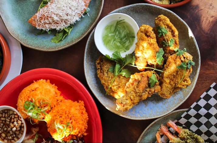 verhead view of crispy fried chicken with herbs, orange rice, and dipping sauces served at Prubechu.