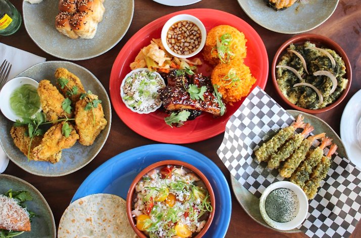 Overhead view of crispy fried chicken with herbs, orange rice, and dipping sauces served at Prubechu.