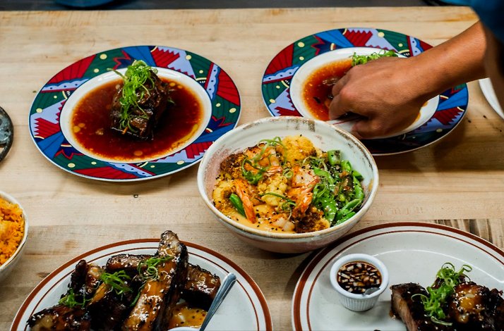 Hands plate and serve a meal of saucy ribs and a shrimp-and-vegetable bowl, served at Prubechu.