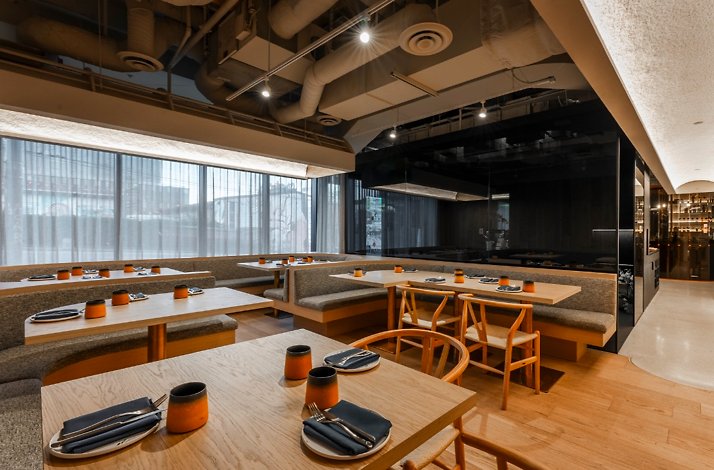 ELEM restaurant's dark-toned host stand adorned with orchids, opening to a warmly lit dining room through glass-panelled doors. 