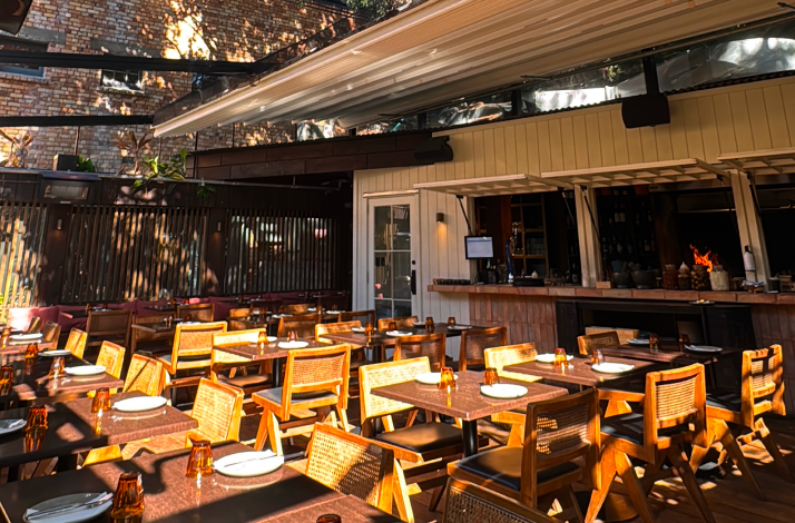 Elegant outdoor dining area and open kitchen setting with tables set for guests.